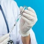 close up picture of doctor's hands holding hypodermic syringe